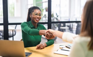 Jeune étudiante souriante serrant la main d'une collaboratrice