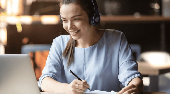 woman working online at her desk with her computer and headphones