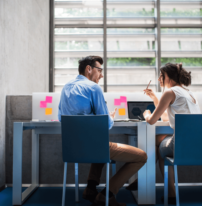 Des étudiants sont assis sur des chaises, faces à un bureau. Ils discutent et l'étudiante de droite